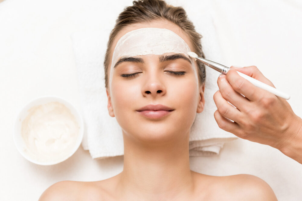 woman getting a facial with a cream kombucha facial masque
