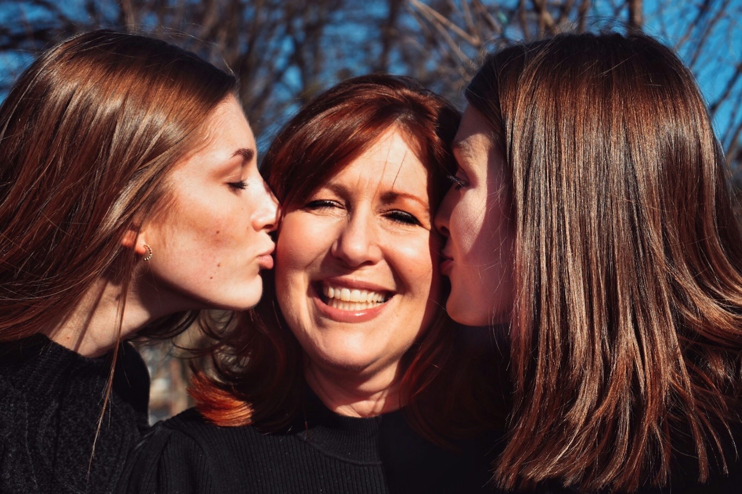 Daughters kissing mom